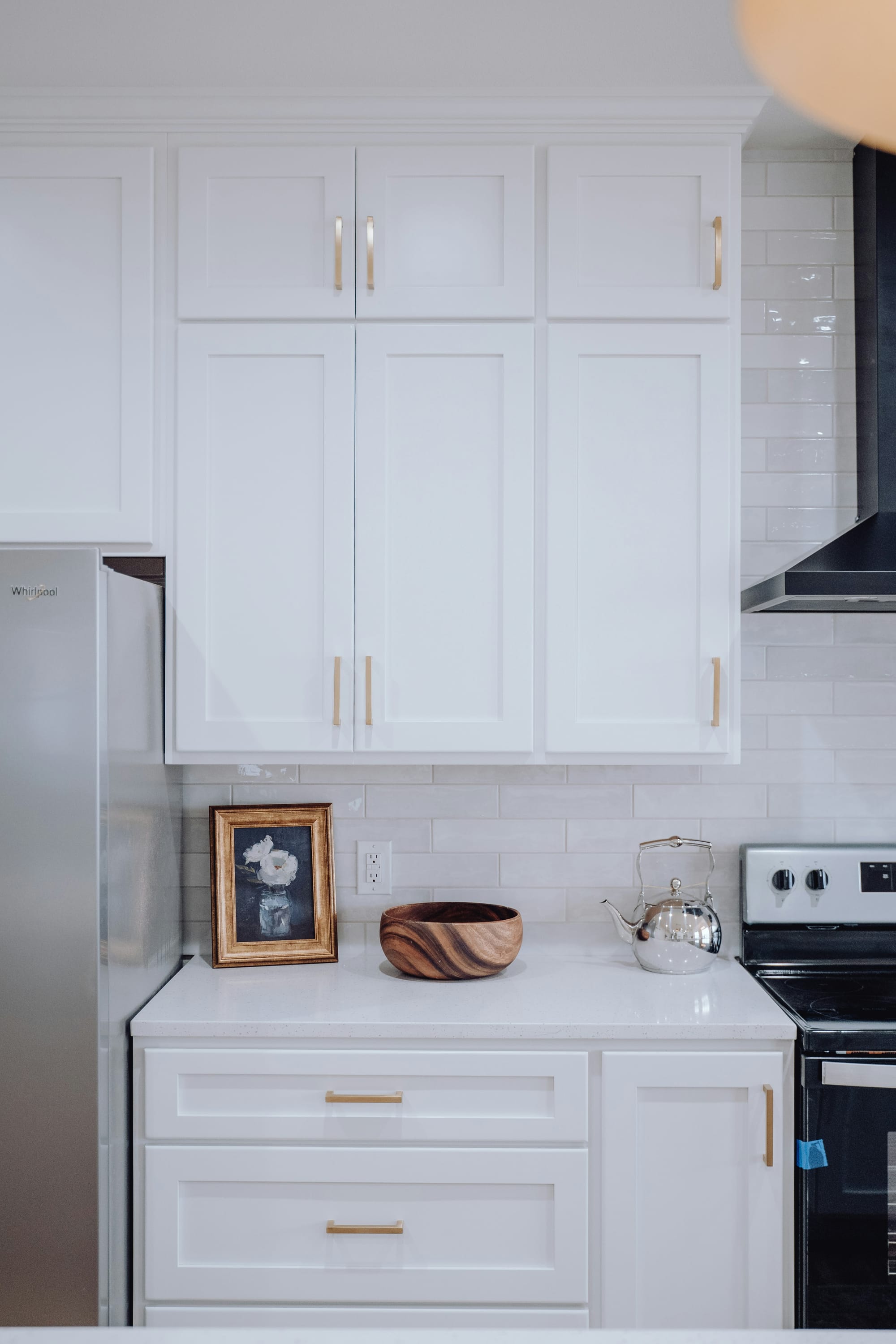 A clean white kitchen with modern cabinets and simple decor.