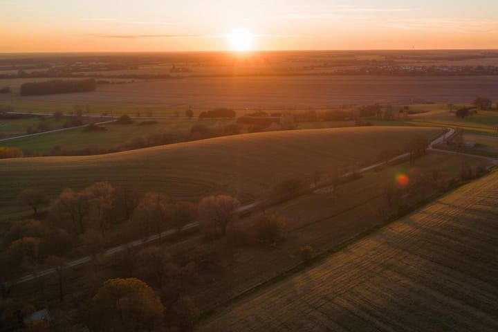 Aerial view of sprawling farmland and open fields bathed in golden sunset light.
