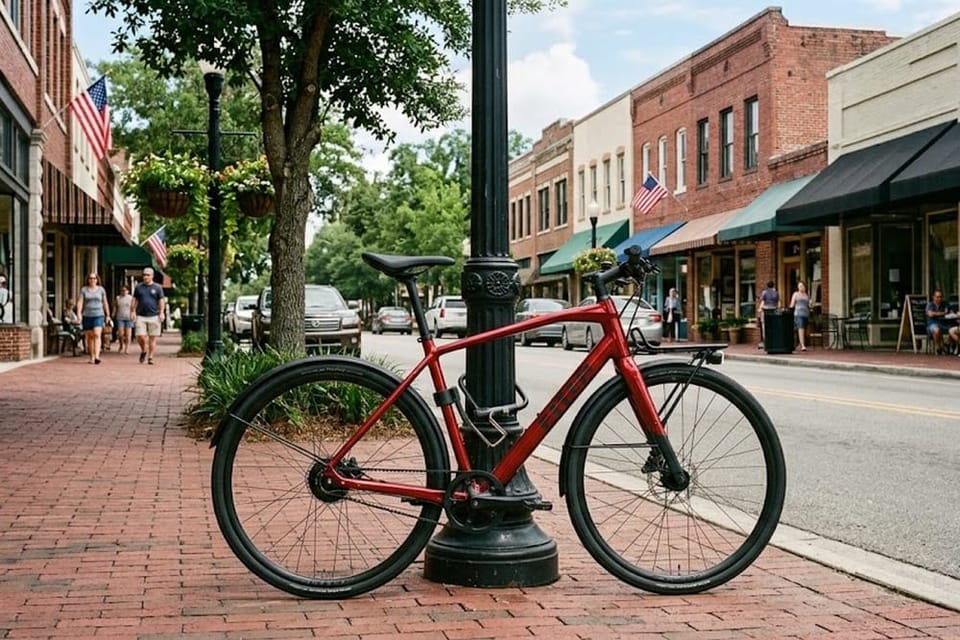 A red bicycle parked on a brick sidewalk along a downtown street.